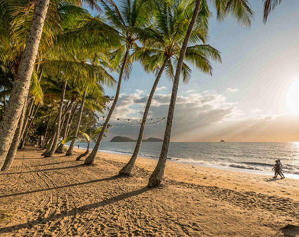 Couple walking along Palm Cove beach at sunset